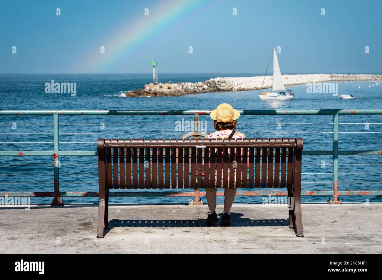 Woman on Pier Bench partaking the scenic harbor view Stock Photo - Alamy