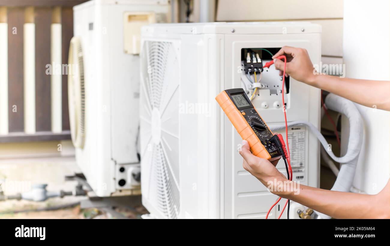 Air conditioner repairman using electricity meter to check air conditioner operation