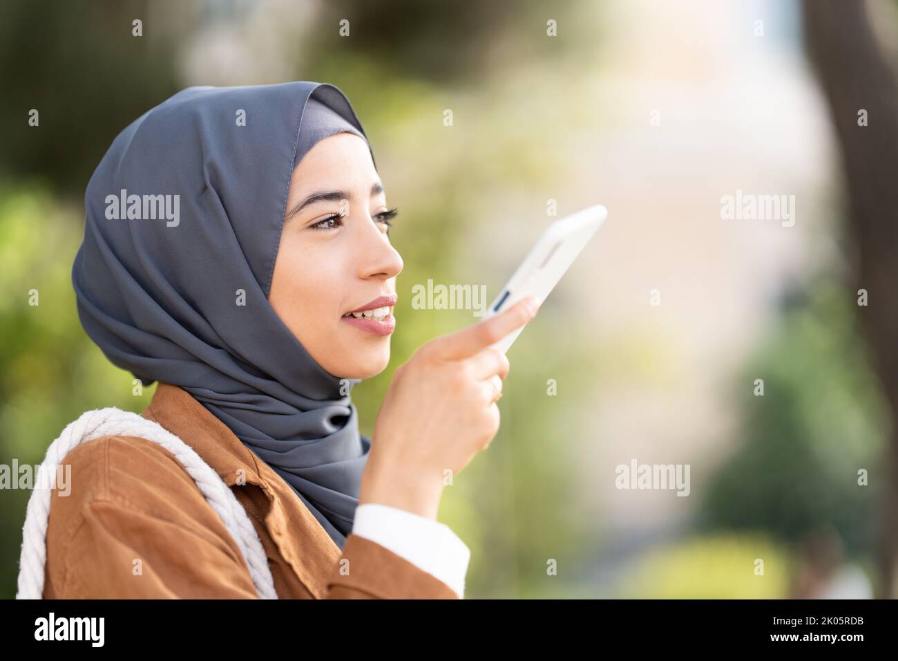 Muslim woman sending a voice message outdoors Stock Photo