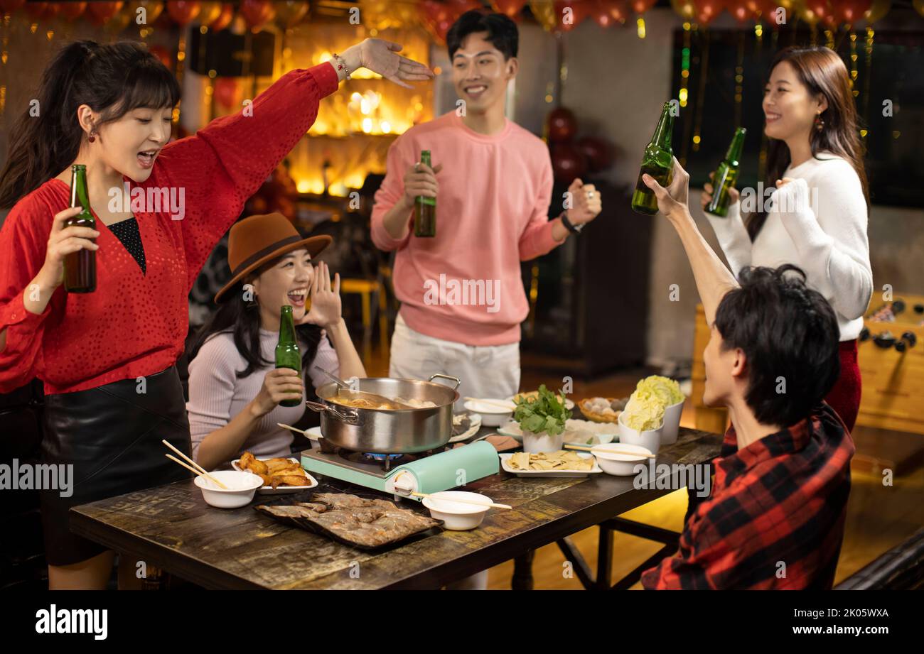 Young Chinese friends drinking beer in hotpot restaurant Stock Photo