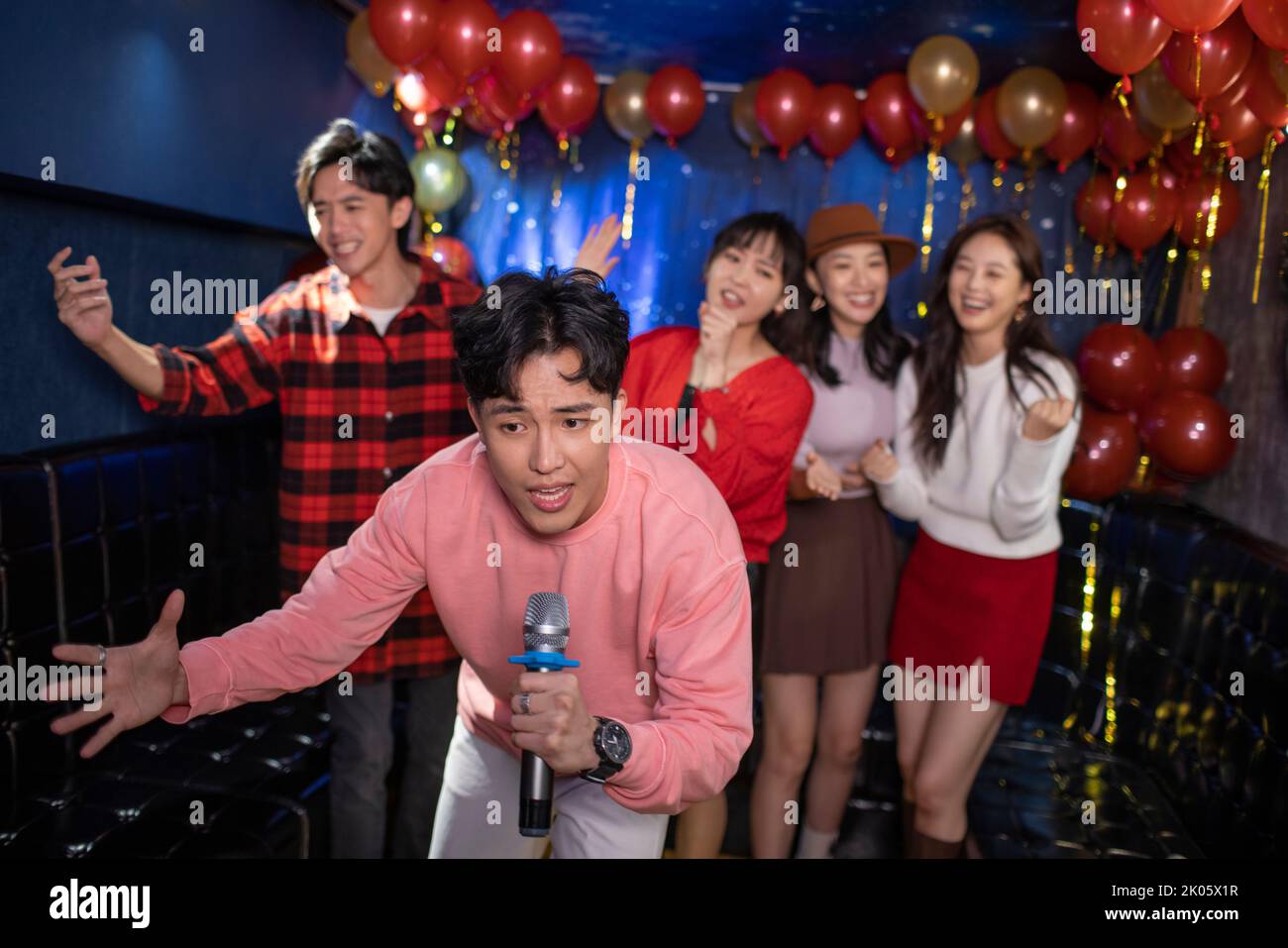 Happy young Chinese friends singing karaoke in nightclub Stock Photo