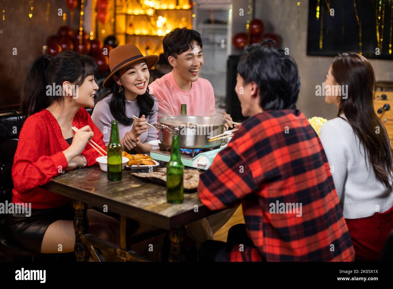 Young Chinese friends having dinner in hotpot restaurant Stock Photo
