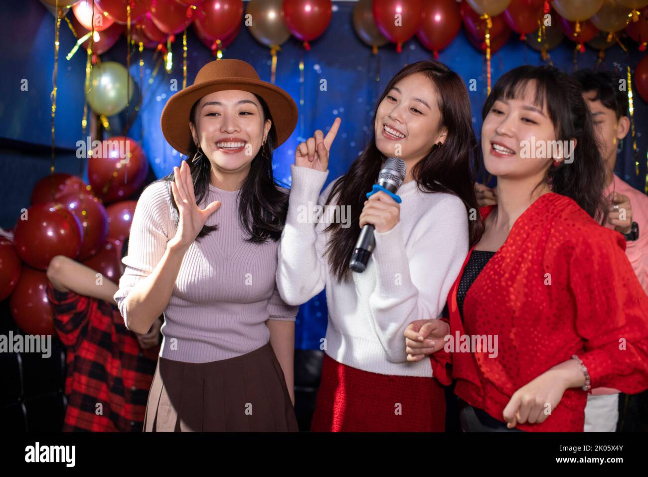 Happy young Chinese friends singing karaoke in nightclub Stock Photo