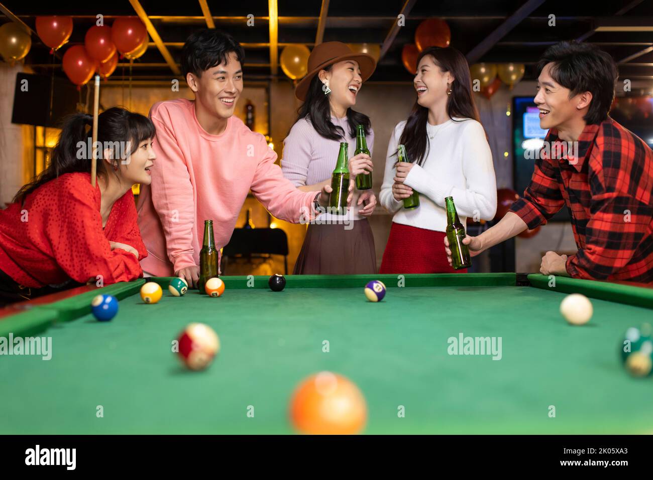 Happy young Chinese friends playing billiard and drinking beer Stock Photo