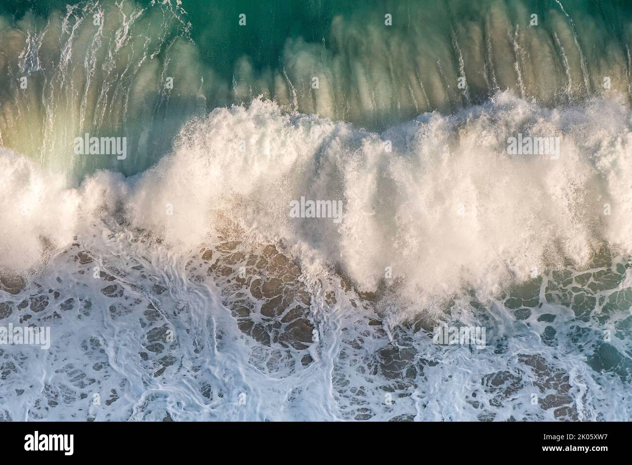 Top view of patterns of white foam from the impact of ocean waves on coastal rocks. South Africa Stock Photo