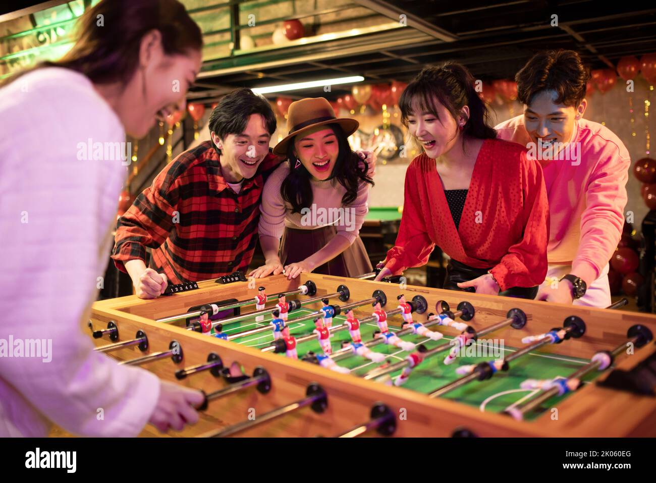 Happy young Chinese friends playing table football Stock Photo