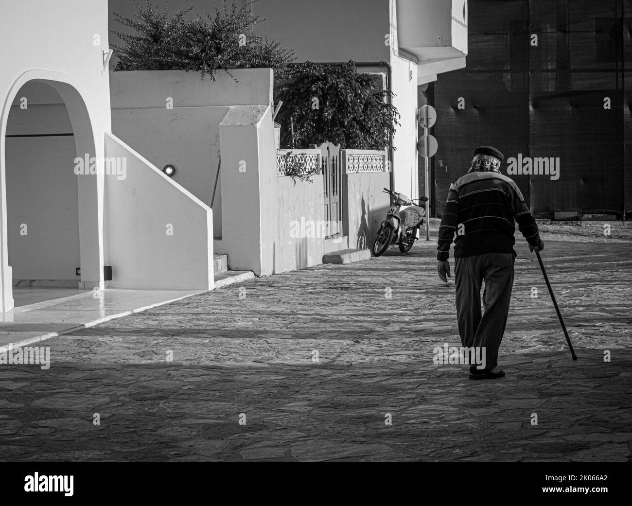 Elderly man with cane walks down the street Stock Photo - Alamy