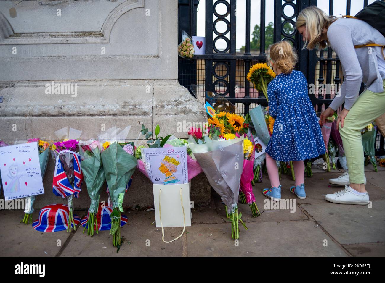 Westminster, London, UK. 10th Sep, 2022. Following the death of the Queen on Thursday members of the public have gathered at Buckingham Palace to honour her passing and to leave flowers, gifts and messages. Young girl placing flowers Stock Photo