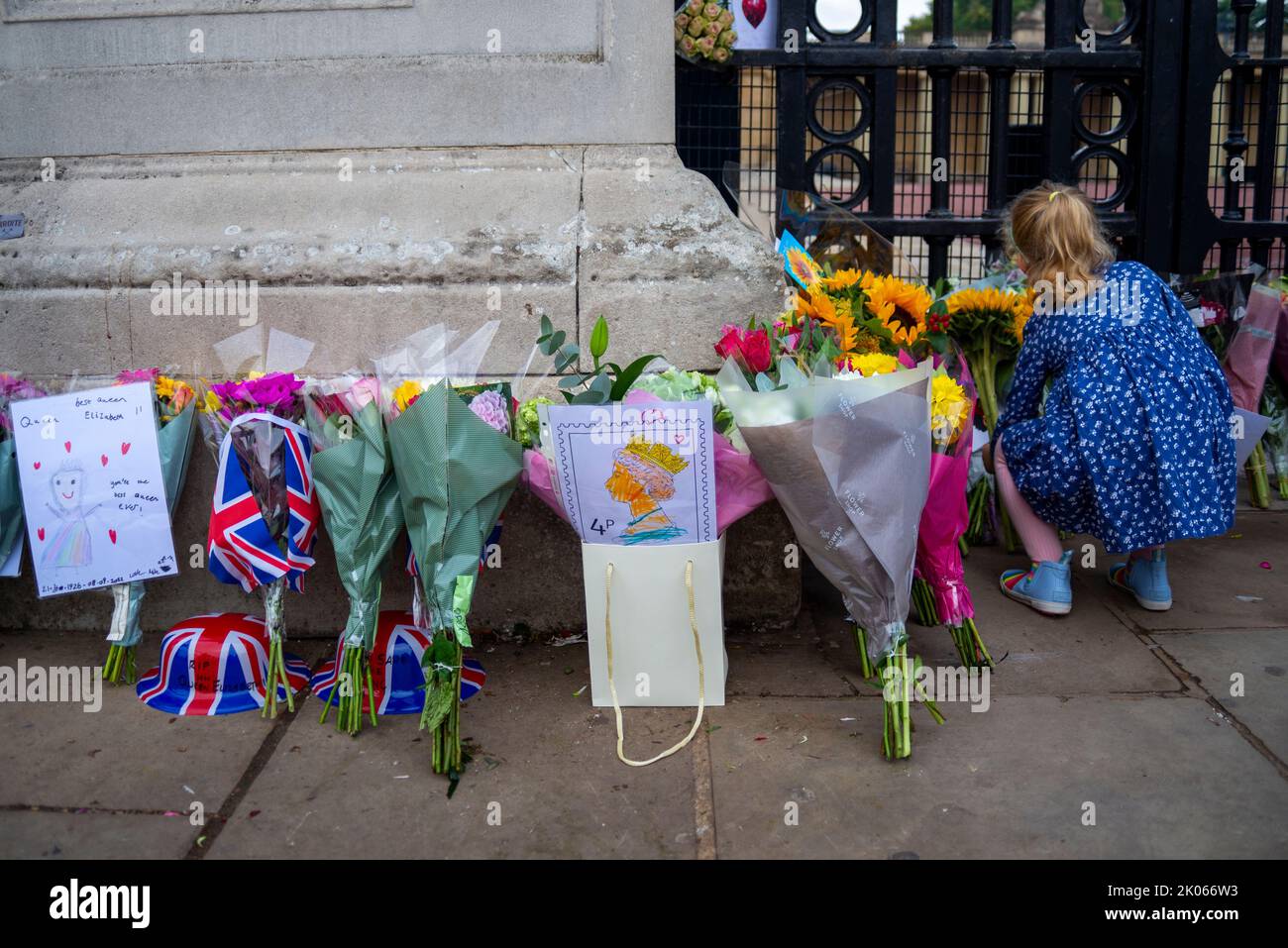 Westminster, London, UK. 10th Sep, 2022. Following the death of the Queen on Thursday members of the public have gathered at Buckingham Palace to honour her passing and to leave flowers, gifts and messages. Young girl placing flowers Stock Photo