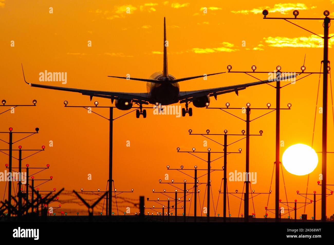 Jet aircraft arriving an airport during sunset with the glowing sun and