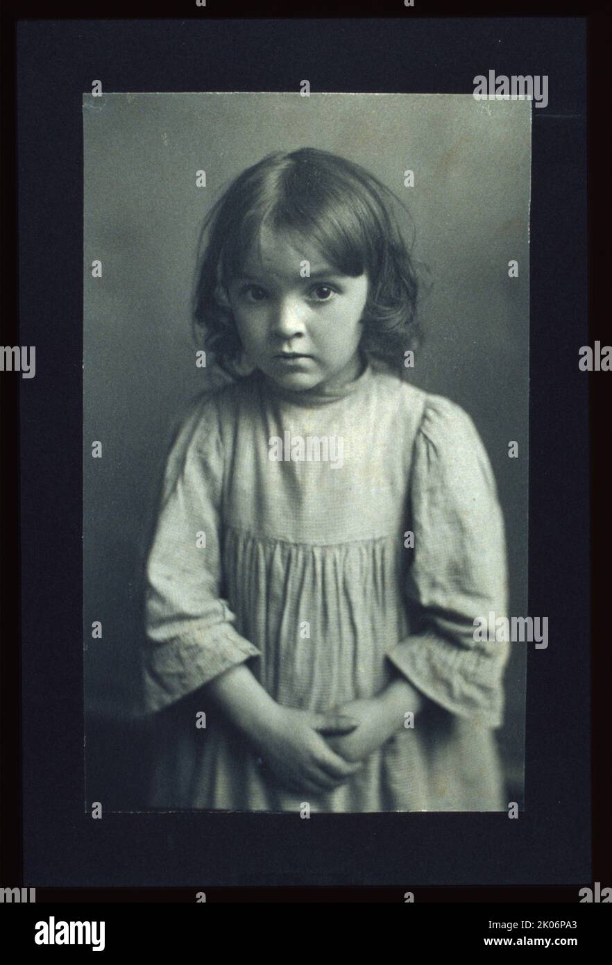 A-listnin' to the witch-tales 'at Annie tells about, c1900. Photograph shows a young girl with her hands clasped in front, staring intently forward. Photograph was an illustration for James Whitcomb Riley's poem &quot;Little Orphant Annie&quot; printed in Brownell's &quot;Dream Children&quot;. Previously attributed to Emma Justine Farnsworth. Stock Photo