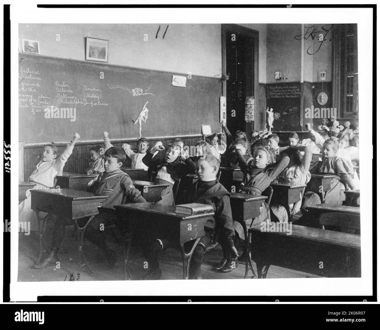 Children seated at desks in Washington, D.C. classroom, stretching, (1899?). Stock Photo