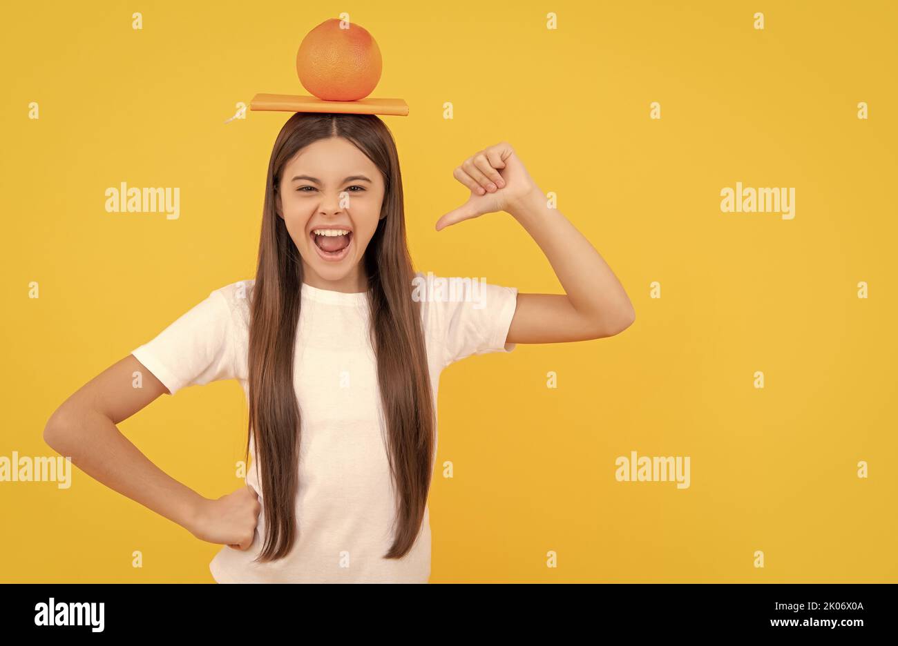 happy child with grapefruit and book on yellow background, vitamin Stock Photo