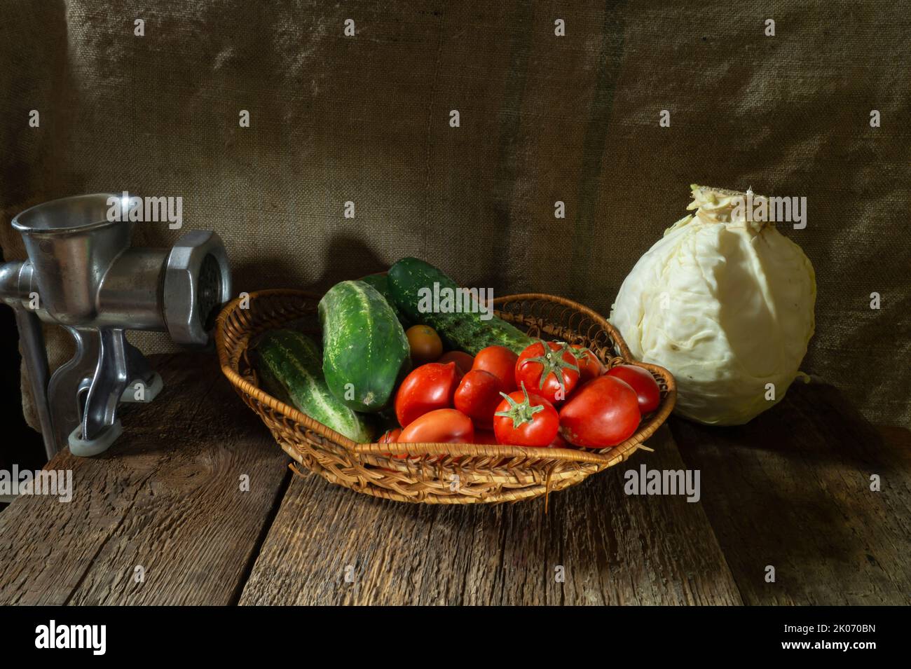 Fresh vegetables in a basket next to a cabbage. Food on a dark background Stock Photo