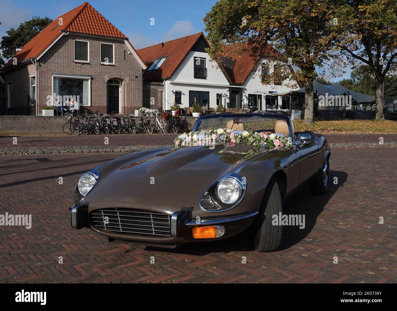 Elburg, Netherlands - Sept 9 2022 A very special rental car for weddings: a cabriolet Jaguar e-type. Some old Dutch houses in the background Stock Photo