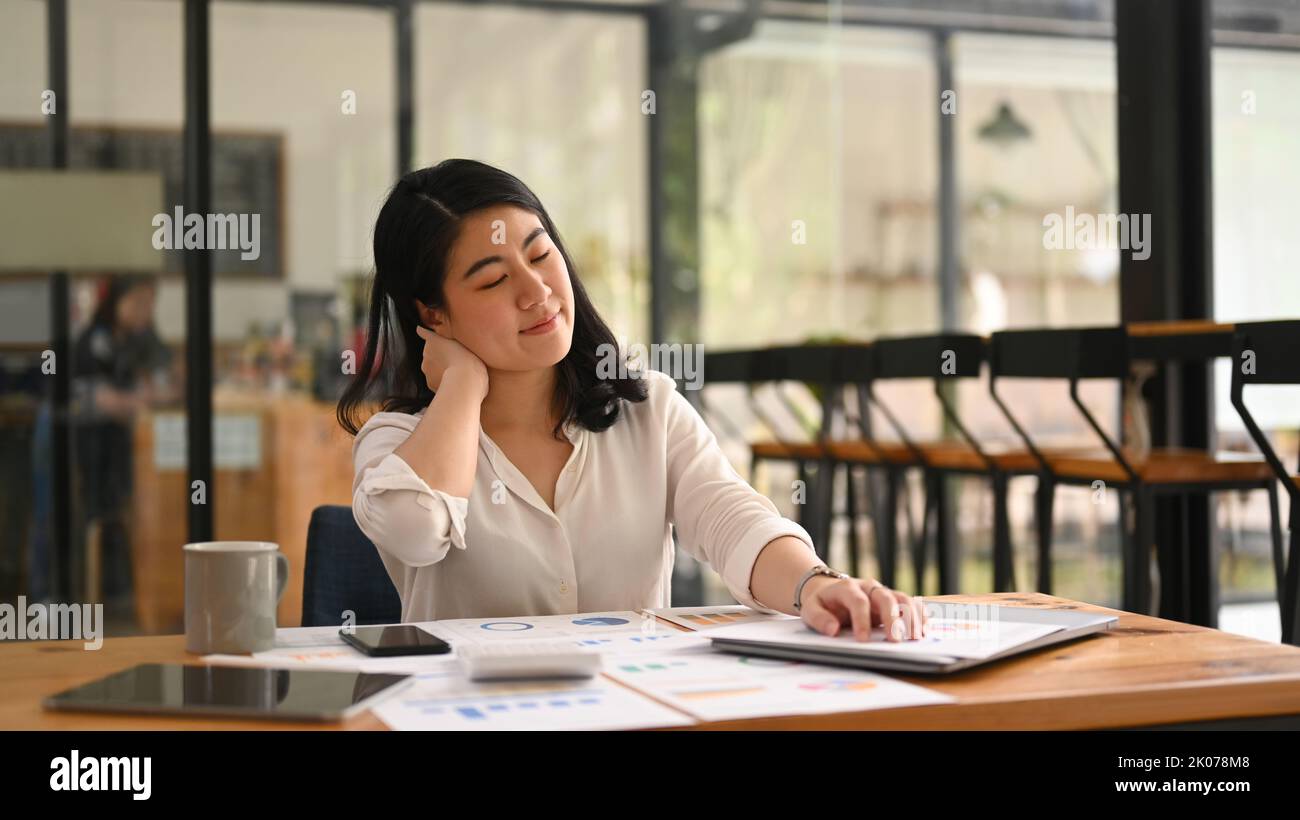 Happy female employee relaxing at work, reclining back in chair and