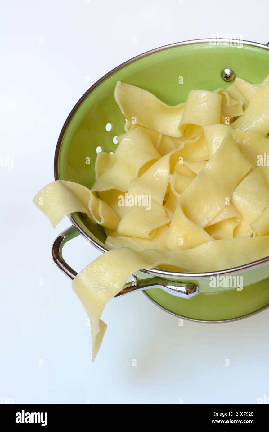 Pappardelle, cooked, wide Italian ribbon noodles in kitchen sieve