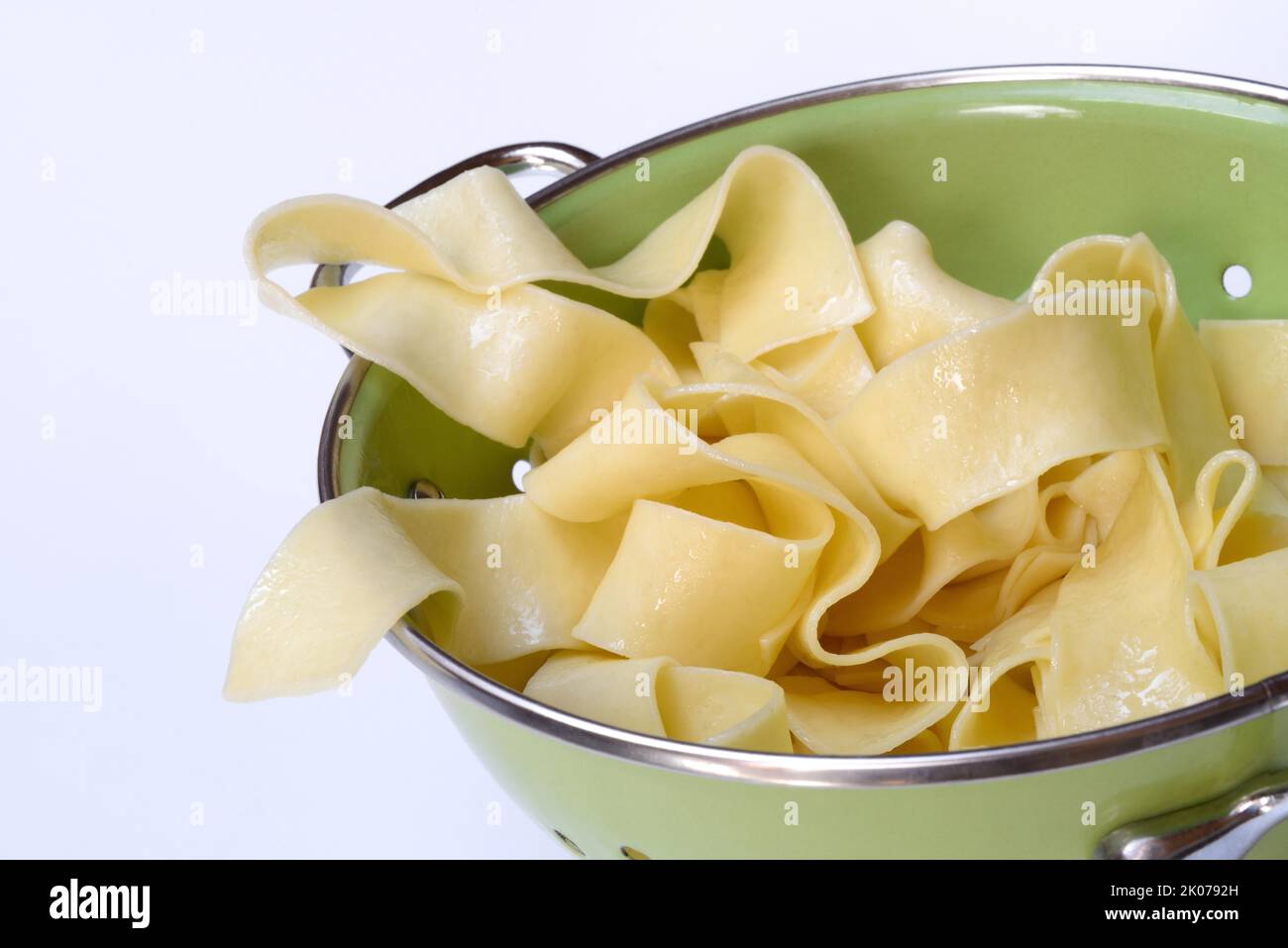 Pappardelle, cooked, wide Italian ribbon noodles in kitchen sieve