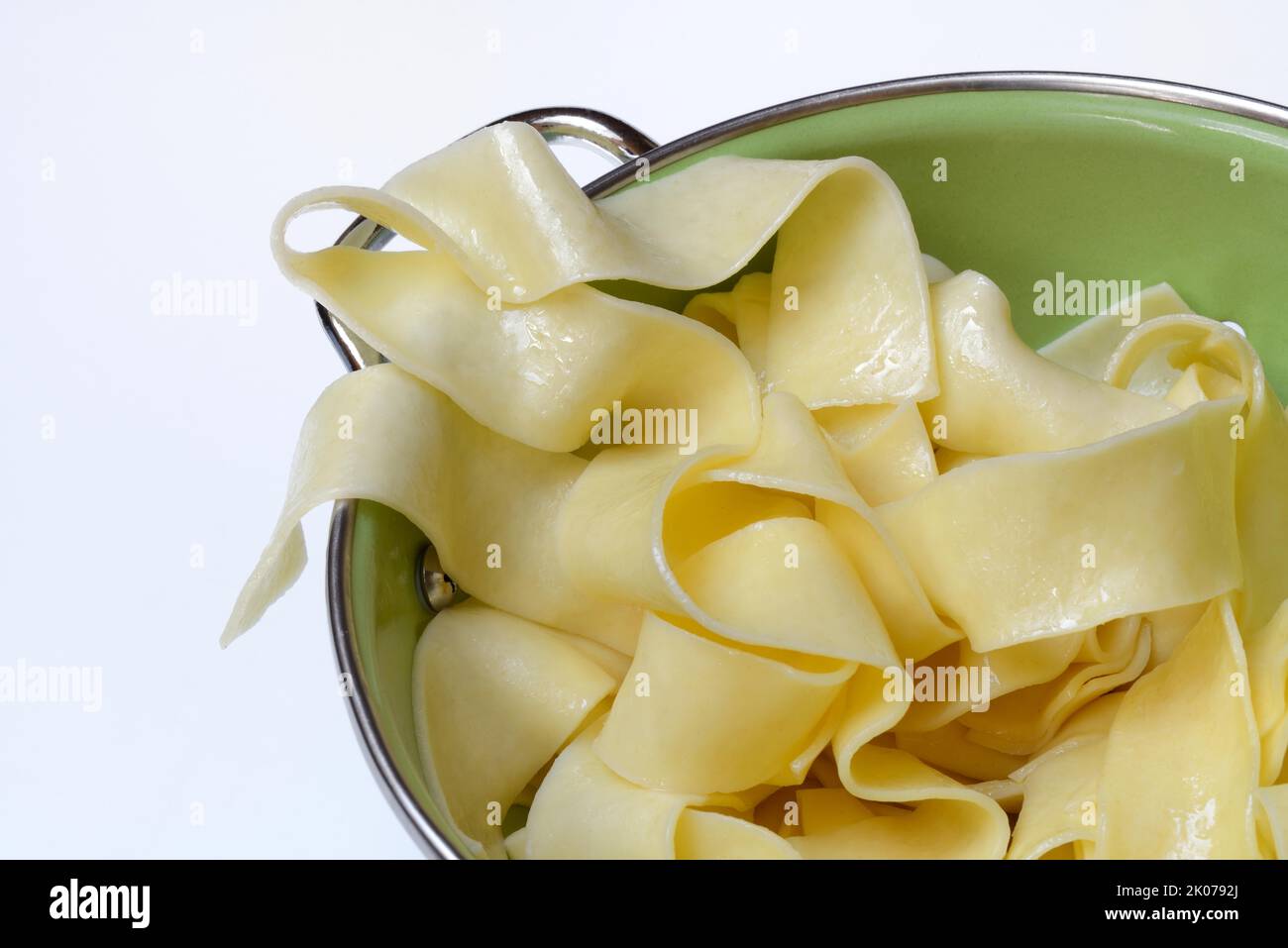 Pappardelle, cooked, wide Italian ribbon noodles in kitchen sieve