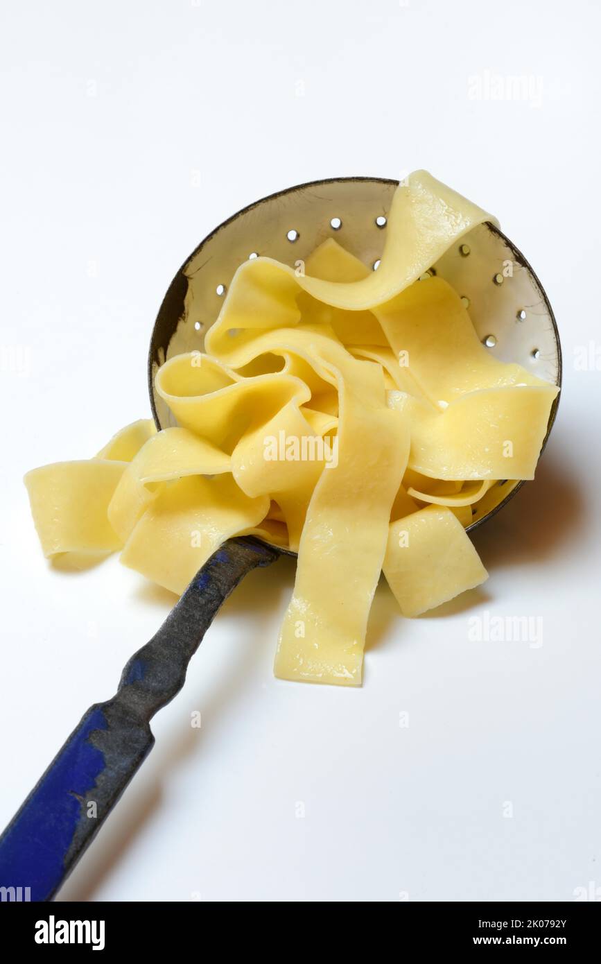 Pappardelle, wide Italian ribbon noodles in a sieve ladle, pasta