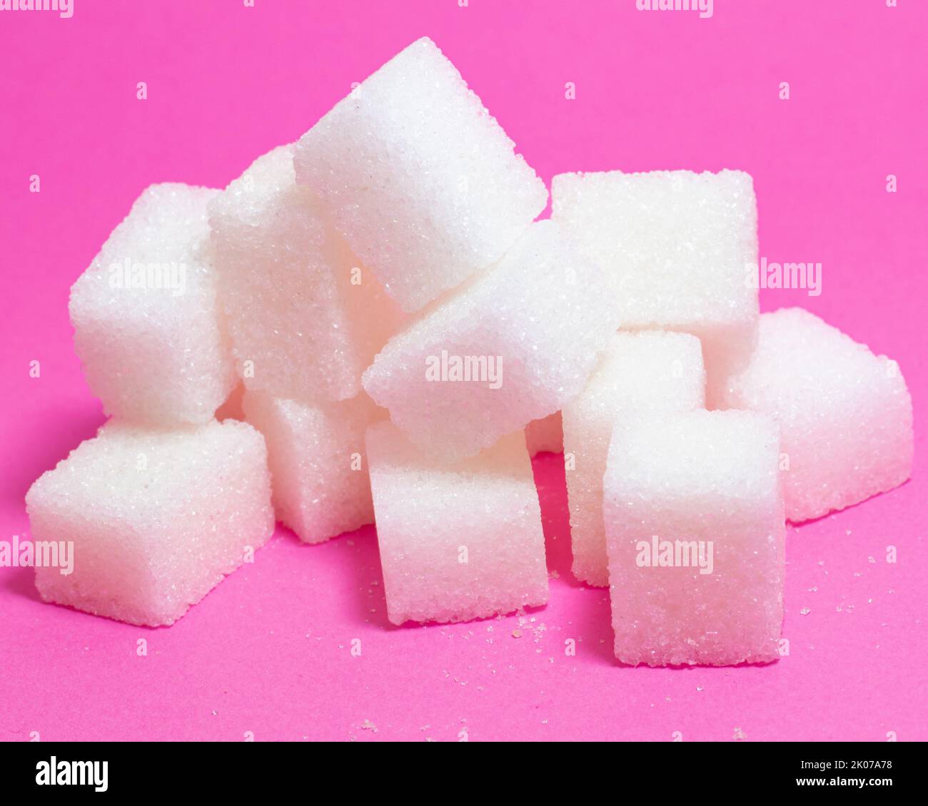 Sugar cubes isolated on pink background. Closeup of pile of sugar