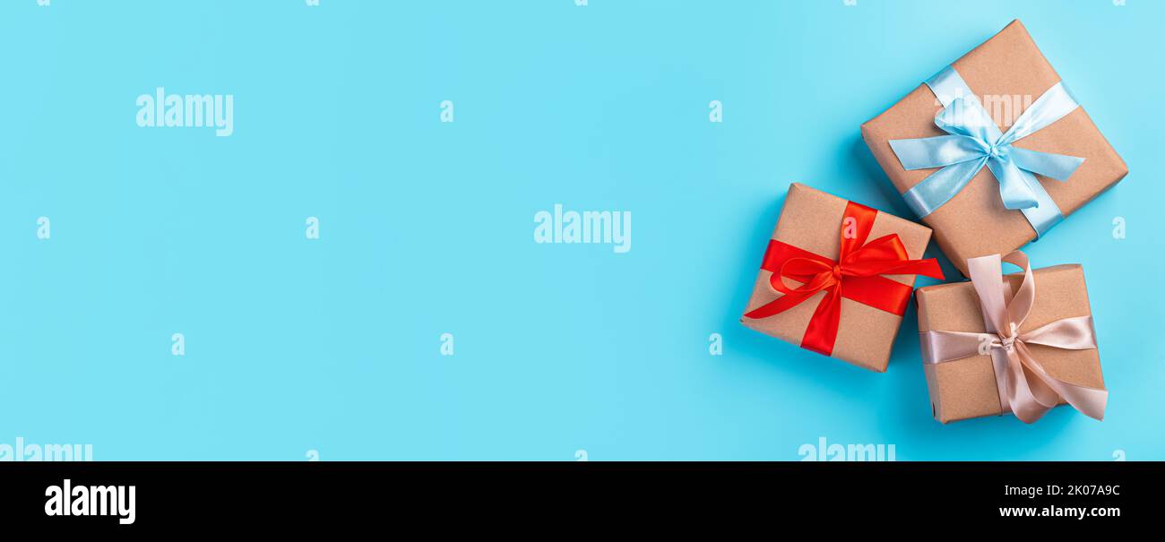 Three gift boxes with colored ribbons on a blue background. Stock Photo