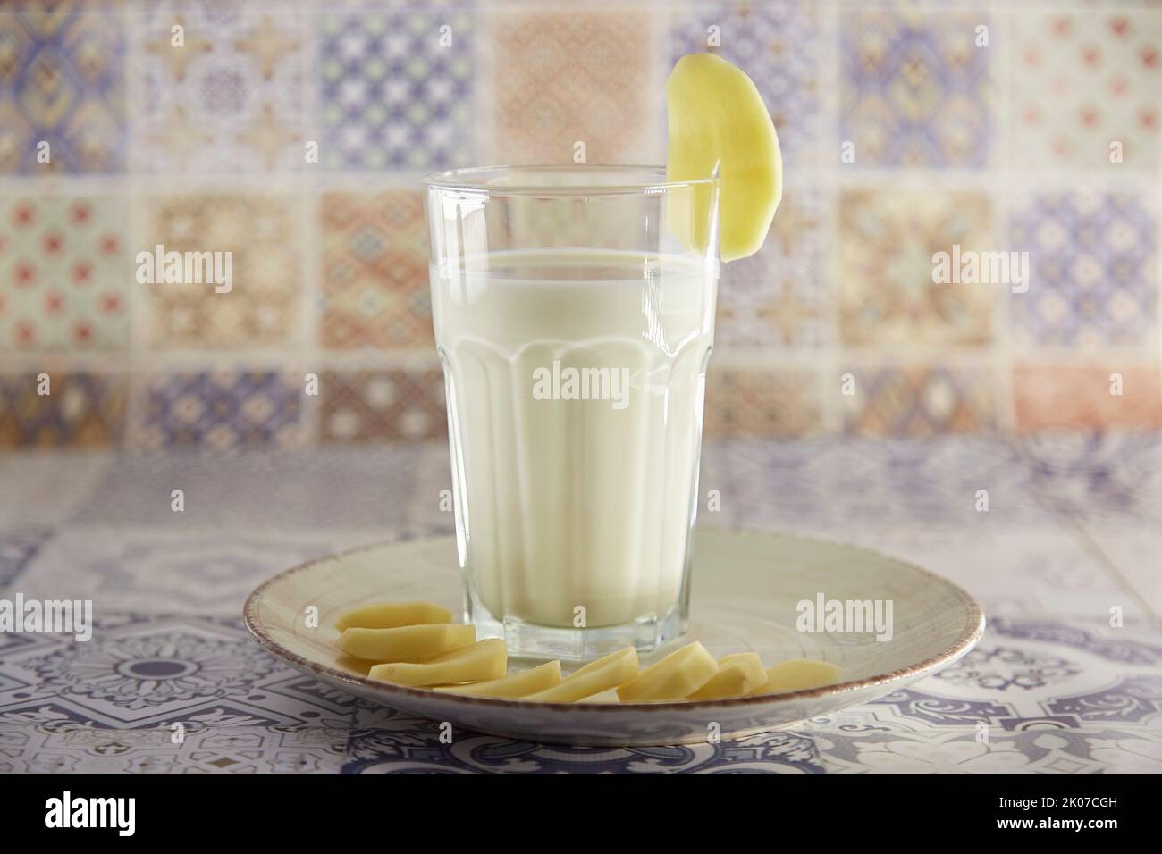 Lactose free, environment friendly potato milk and potato on the plate on the table. Alternative, non-dairy milk. Tile classic background. Copy space. Stock Photo