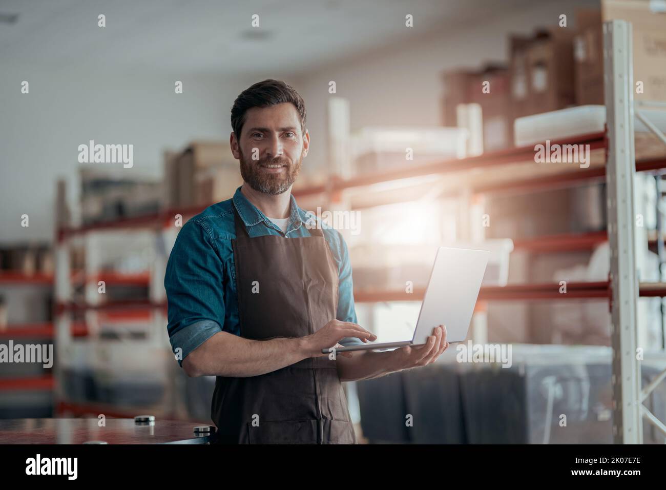 Male worker working laptop on background of warehouse  Stock Photo