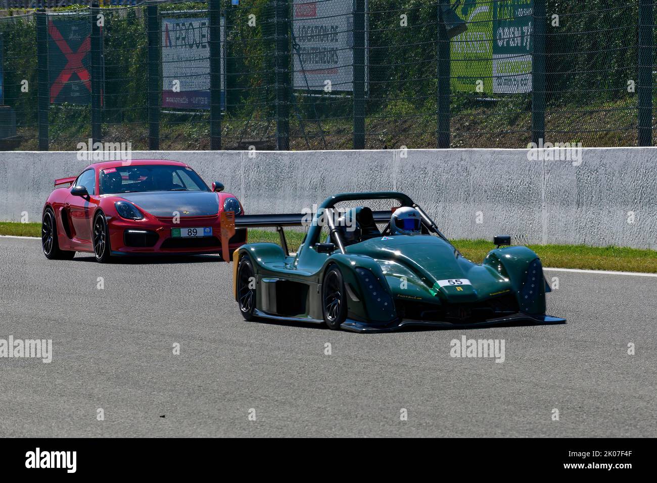 Radical SR10 openwheel racing car in front behind Porsche Cayman GT4 races at high speed top