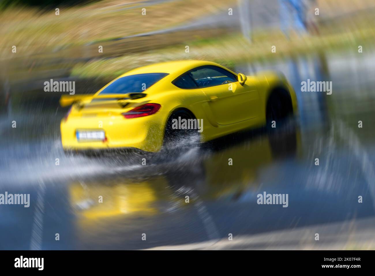 Sports car racing car Porsche Cayman GT4 on artificially rain wet road during driving safety training skids due to aquaplaning, in the foreground Stock Photo