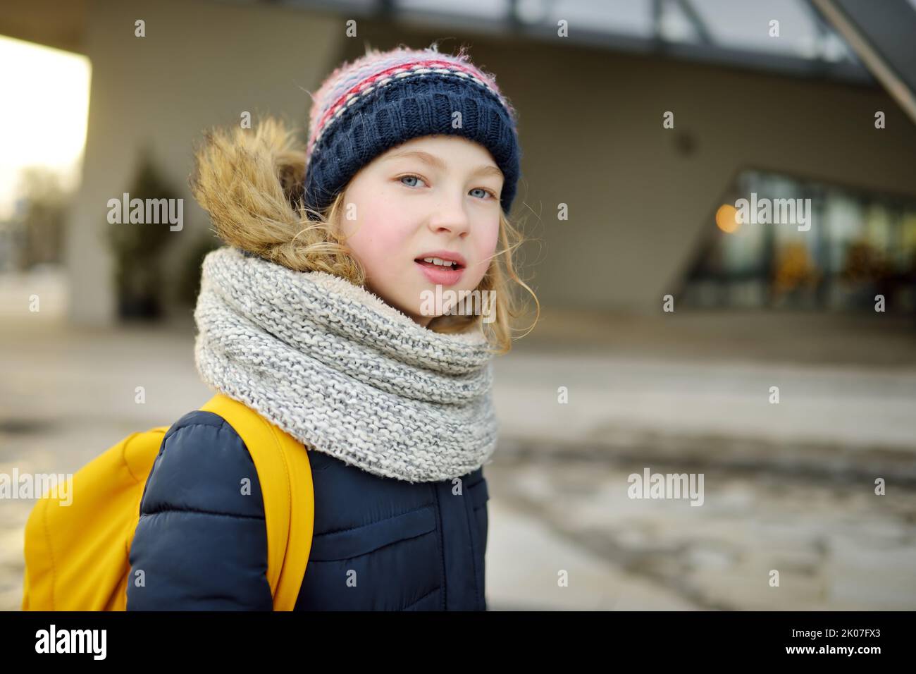 Cute young girl with a backpack heading to school on cold winter