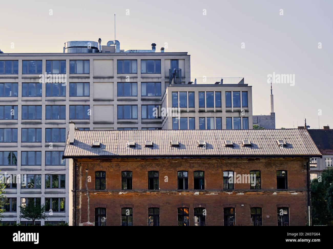 Empty demolition brick house in front of a modern residential building and concrete office building, contrasting architecture Stock Photo
