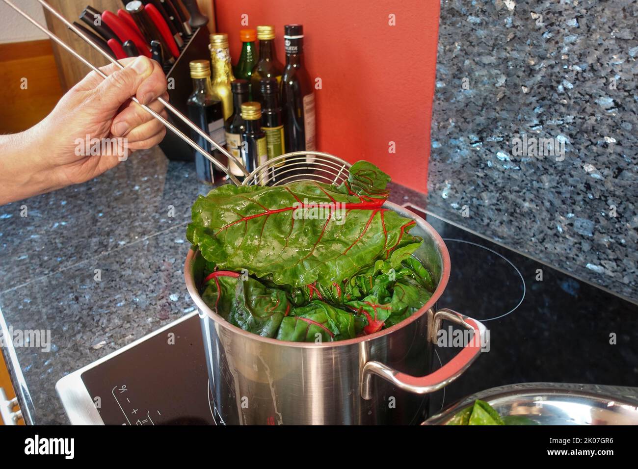 Beetroot (Beta vulgaris subsp. vulgaris), blanching chard leaves, cooking pot, slotted spoon
