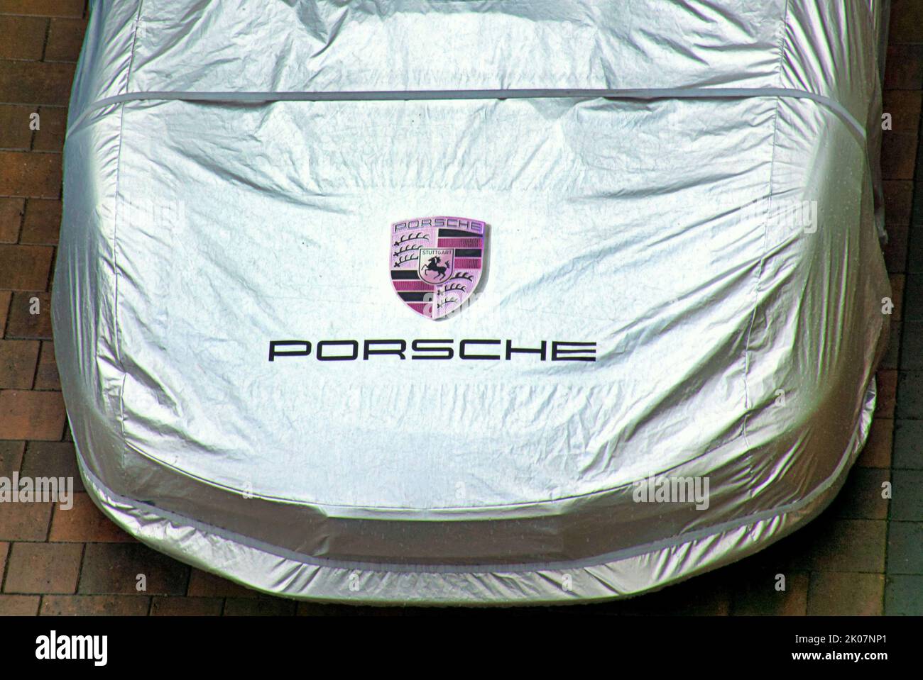 Porsha car under silver  cover with logo on street Stock Photo
