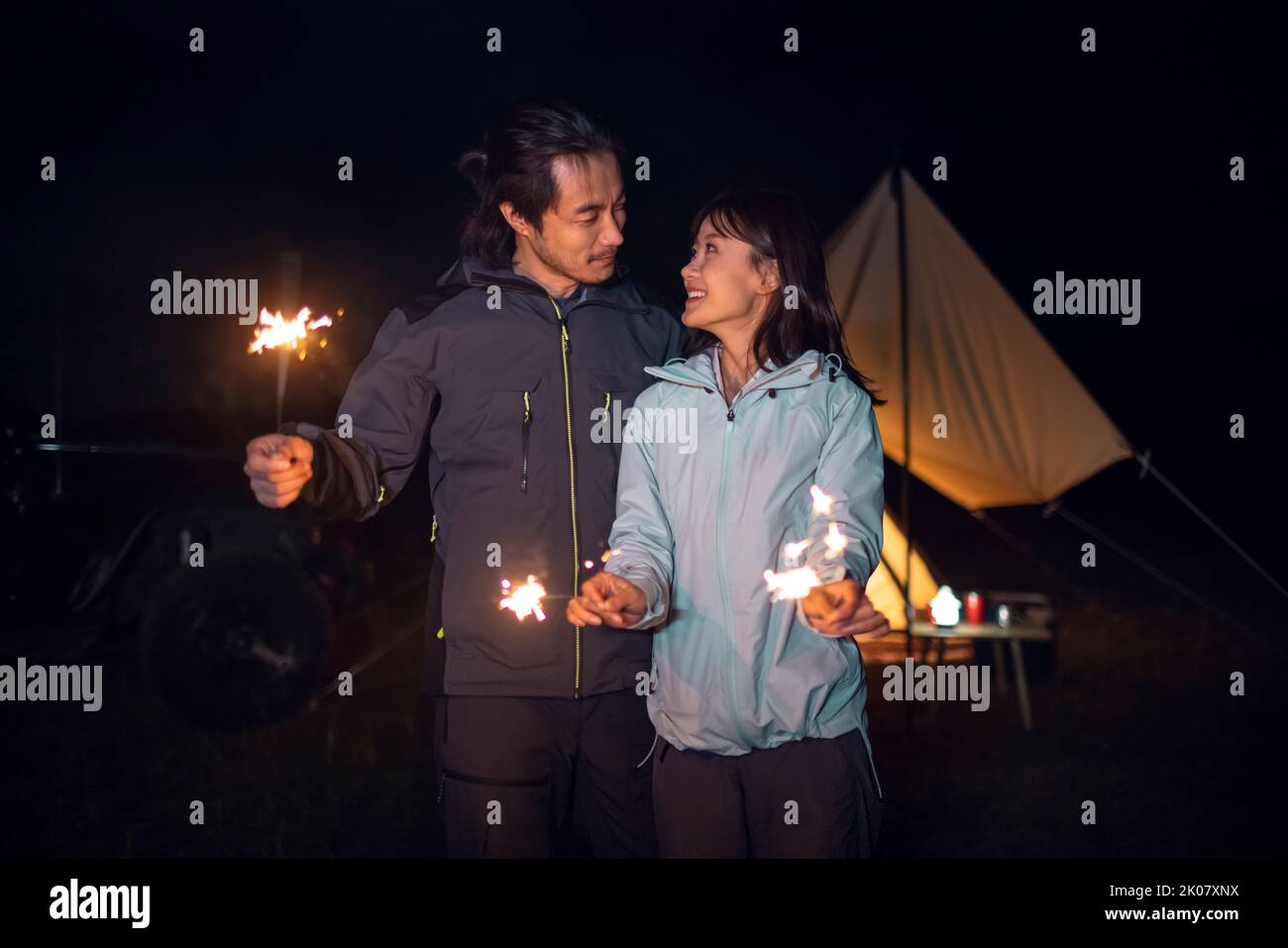 Happy Chinese couple holding sparklers and camping outdoors Stock Photo