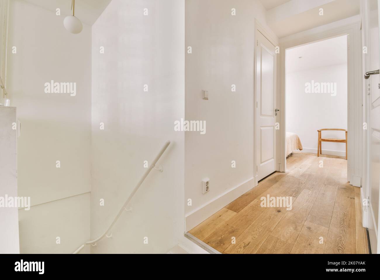 White hallway with wooden stairway leading to second floor of modern ...