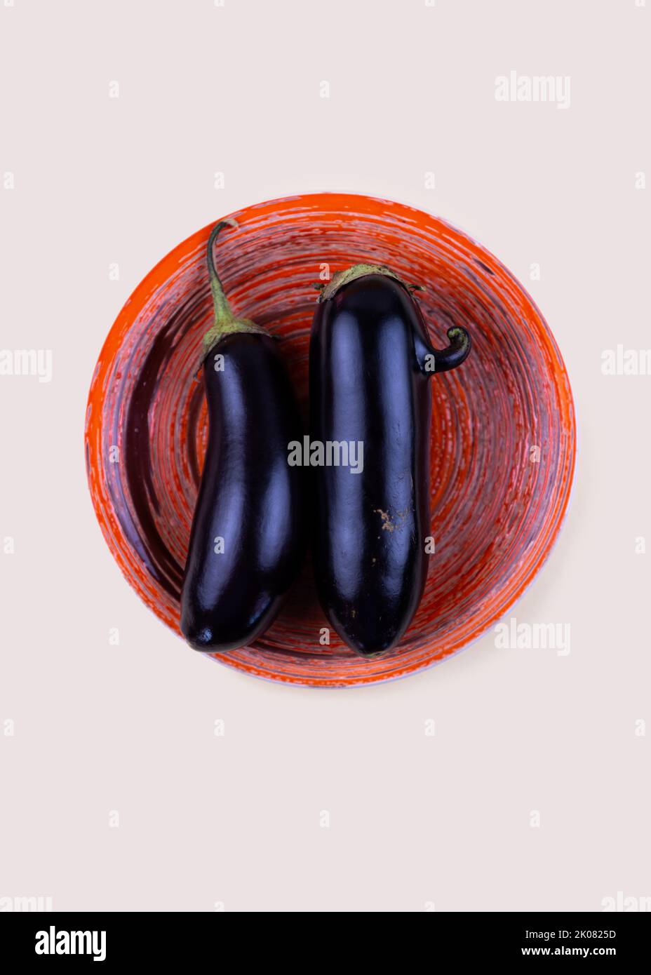 Ugly eggplant with nose and normal eggplant on orange plate. Funny