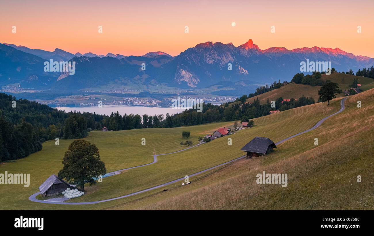 A beautiful summer morning during sunrise and the moon slowly descending behind the mountains. The climatic health resort of Heiligenschwendi is situa Stock Photo