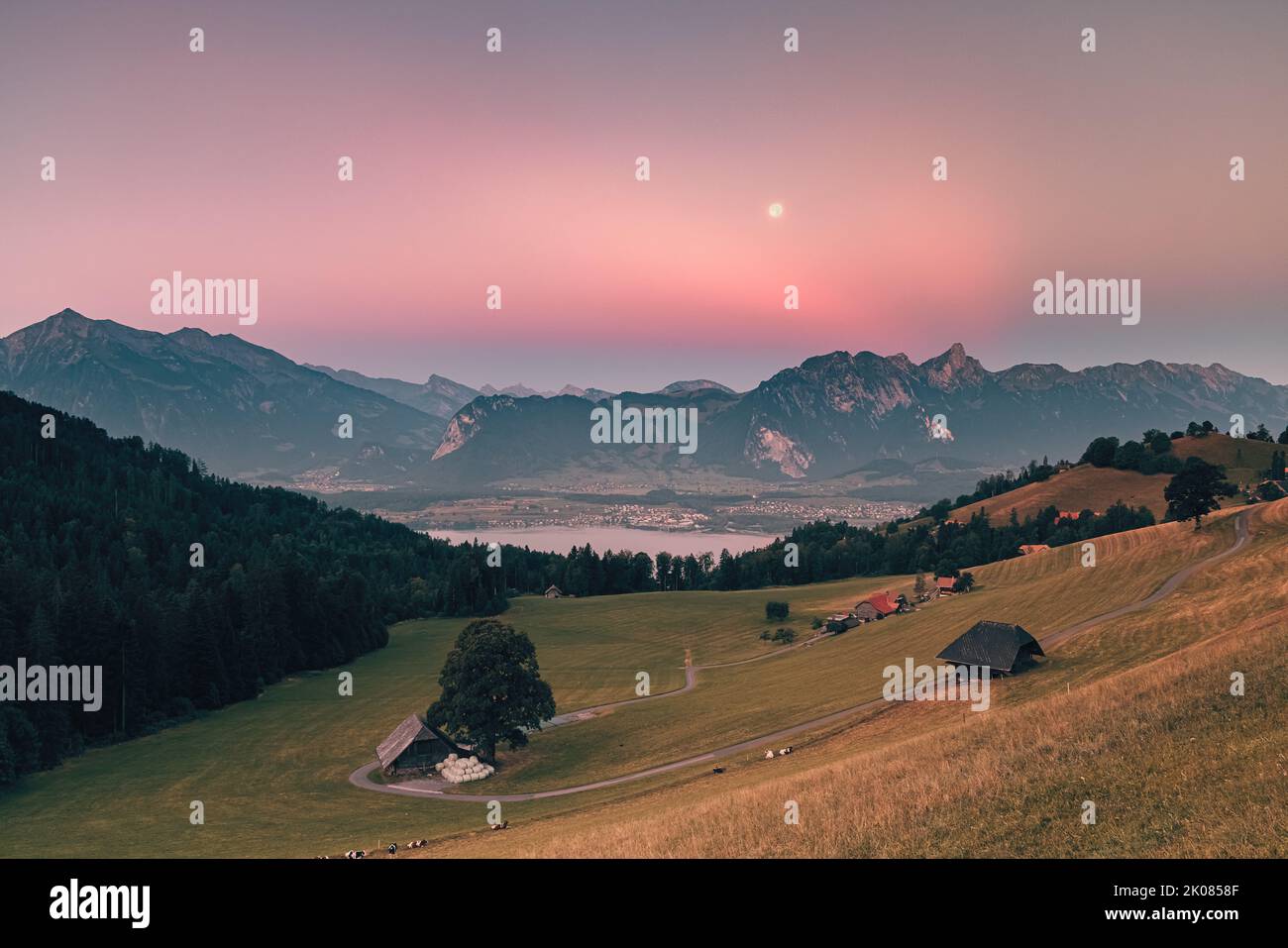 A beautiful summer morning during sunrise and the moon slowly descending behind the mountains. The climatic health resort of Heiligenschwendi is situa Stock Photo