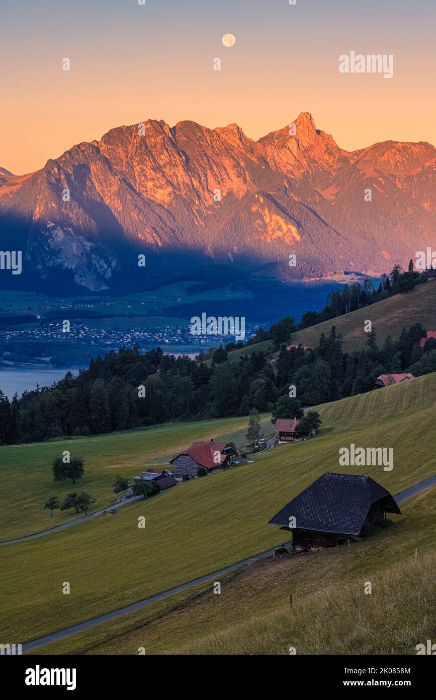 A beautiful summer morning during sunrise and the moon slowly descending behind the mountains. The climatic health resort of Heiligenschwendi is situa Stock Photo