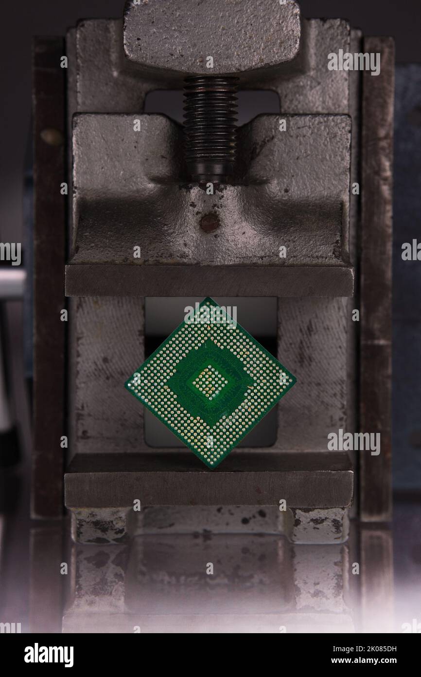 an electronic chip between the jaws of a vice Stock Photo
