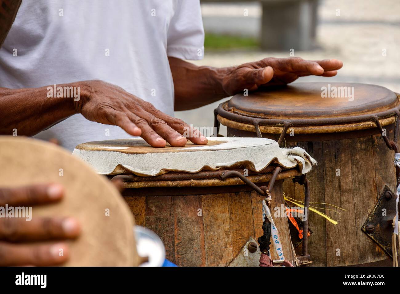 Percussionist playing a rudimentary atabaque during afro-brazilian capoeira fight presentation in the streets of Pelourinho in Salvador city, Bahia Stock Photo