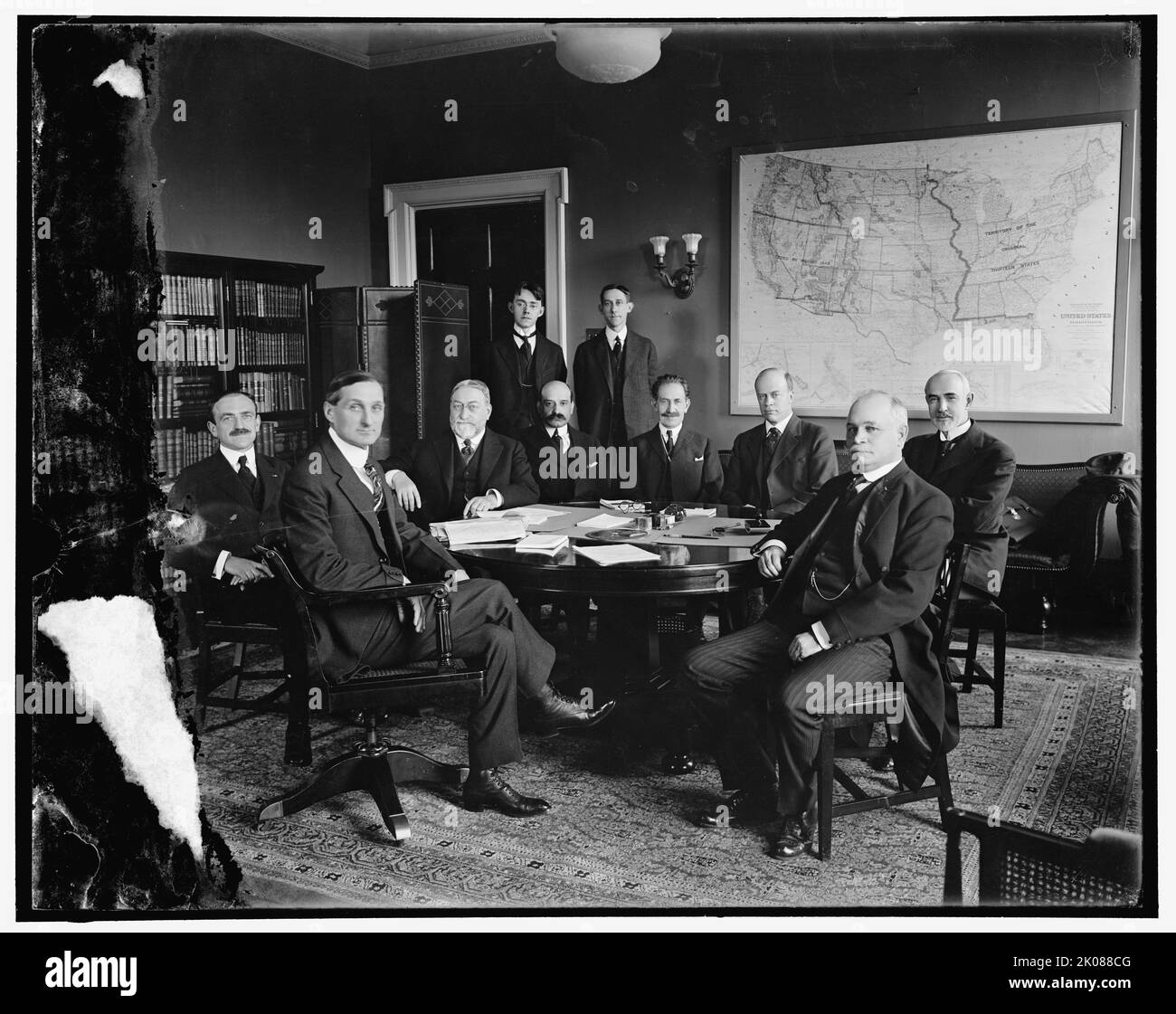 International High Commission, between 1910 and 1920. American lawyer and politician William Gibbs McAdoo Jr. (2nd left) was the husband of Eleanor Wilson McAdoo, (daughter of president Woodrow Wilson). Note map on wall of United States Territories and Insular Possessions, showing 'Original Thirteen States'. Stock Photo