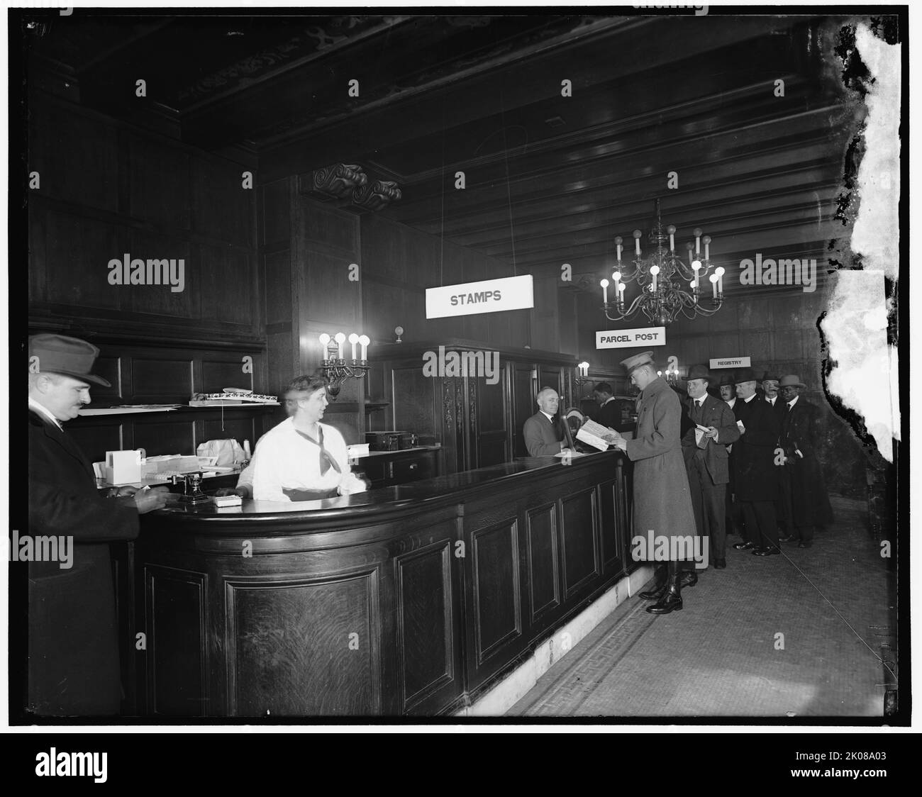 Riggs Bldg. Post Office, between 1910 and 1920. Postal workers and customers, USA. Note scales at left for weighing parcels. Stock Photo