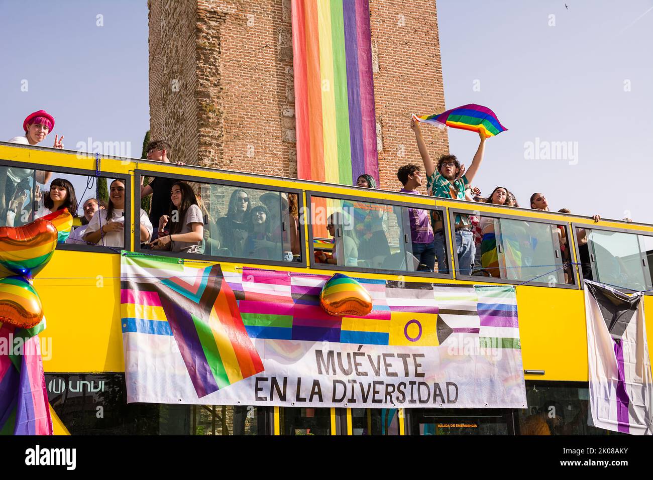 Alcala de Henares, Spain - June 18, 2022: Open bus with LGBTQ protesters for gay pride in front of the Saint Mary Tower Stock Photo