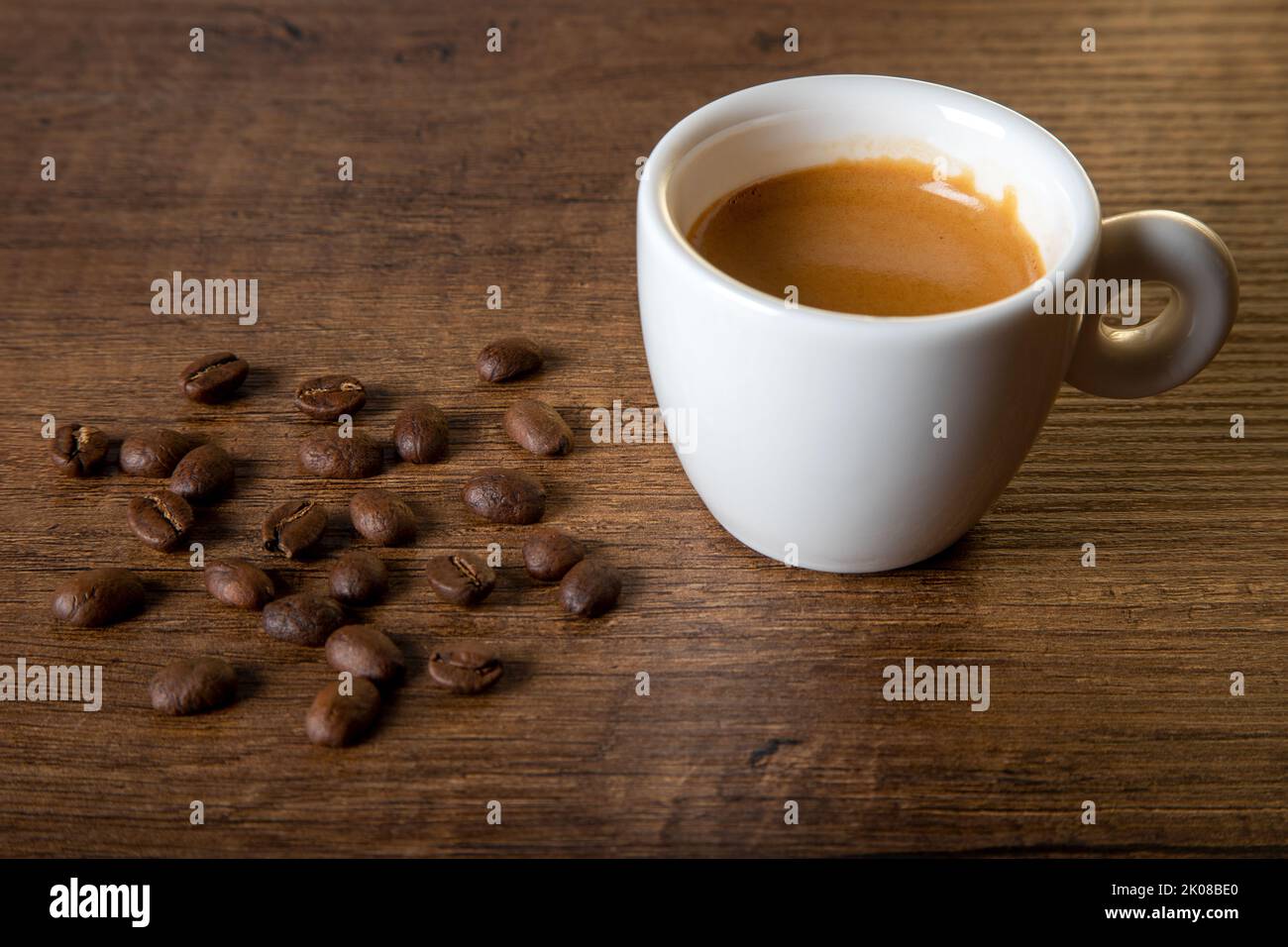 White cup of espresso with coffee beans on wooden background Stock Photo