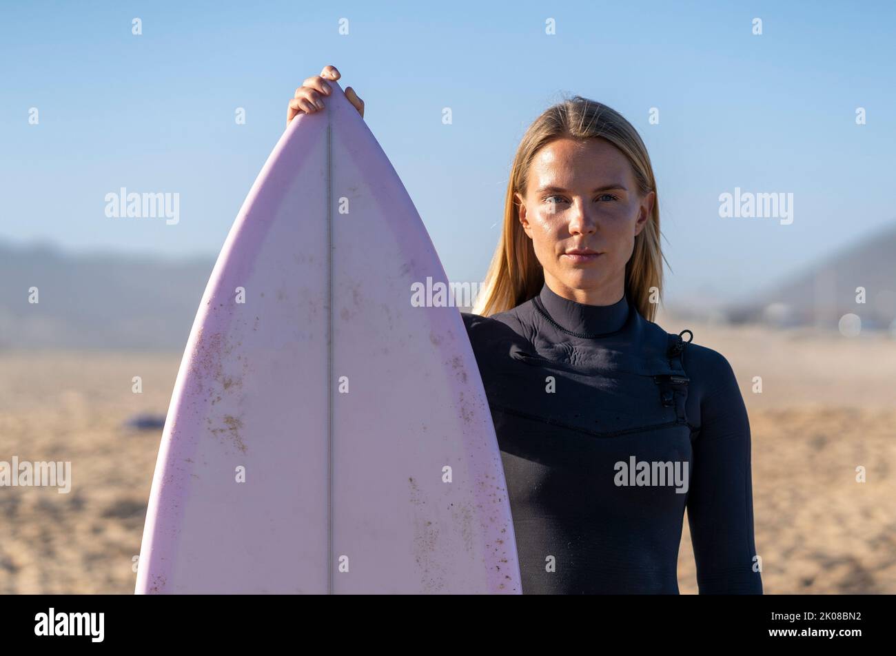 Surfer girl at the beach with her surfboard. Female surfer woman Stock Photo