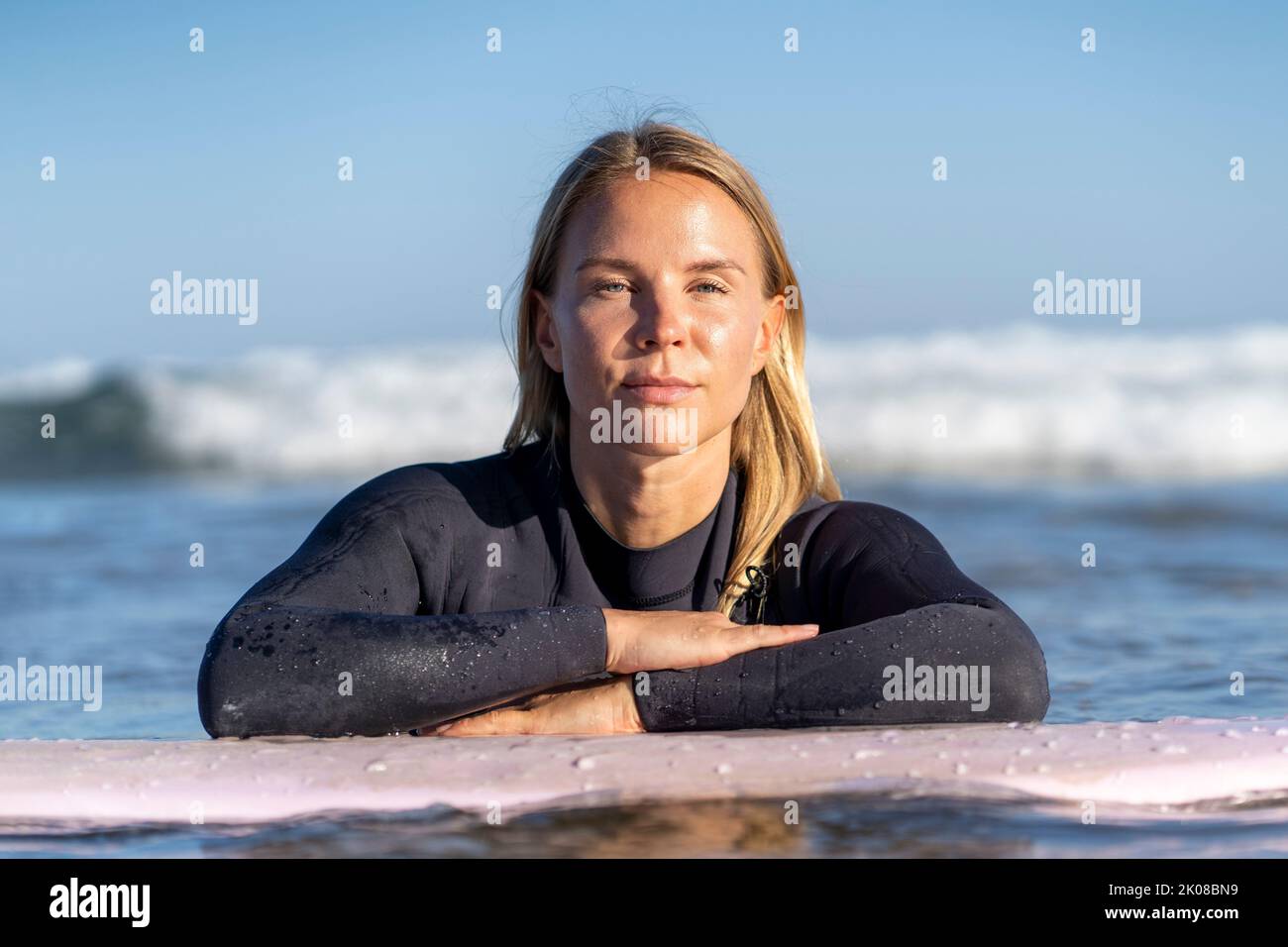 Surfer girl with her surfboard looking at the camera. Female surfer woman Stock Photo