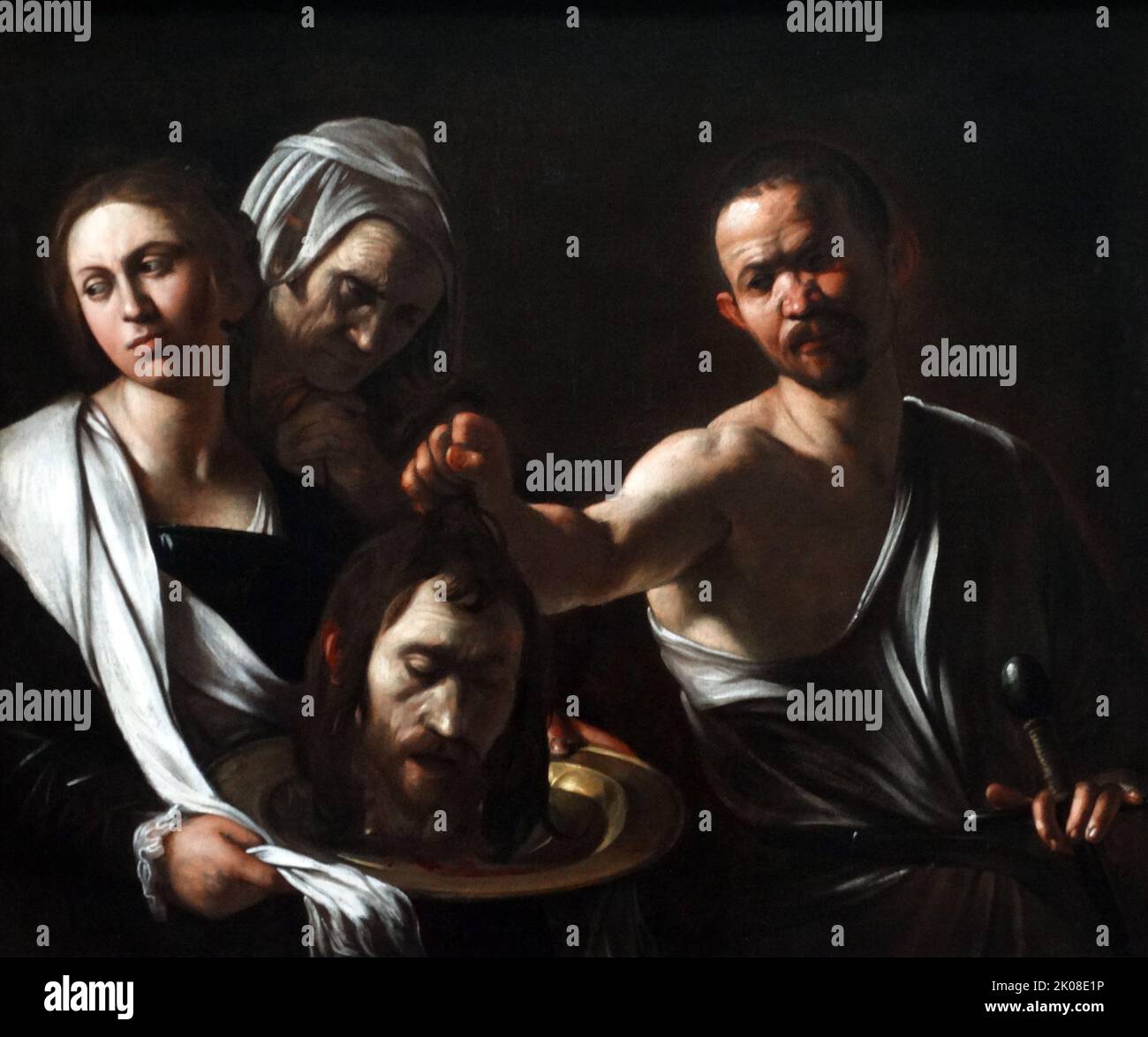 Caravaggio (1571-1610) painting titled: Salome with the Head of John the Baptist. The canvas shows Salome, daughter of queen Herodias, holding in her hands the tray with the head of the prophet John the Baptist, who according to the Holy Gospels was beheaded by order of King Herod Antipas after having promised the latter to his stepdaughter Salome that, if she agreed to dance before him, she would give him whatever he wanted. And when the young woman asked him to give him the head of the Baptist, the king was upset because he appreciated it, but in the end he agreed to his wishes and ordered t Stock Photo