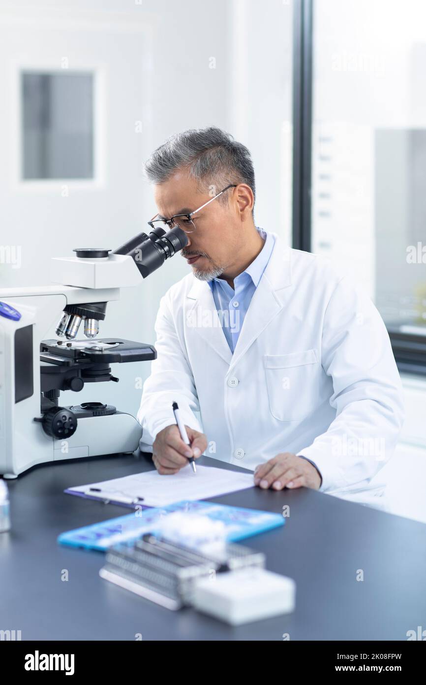 Chinese scientist looking through a microscope Stock Photo Alamy